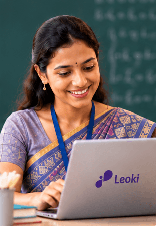 A teacher working on a laptop in front of a chalkboard
